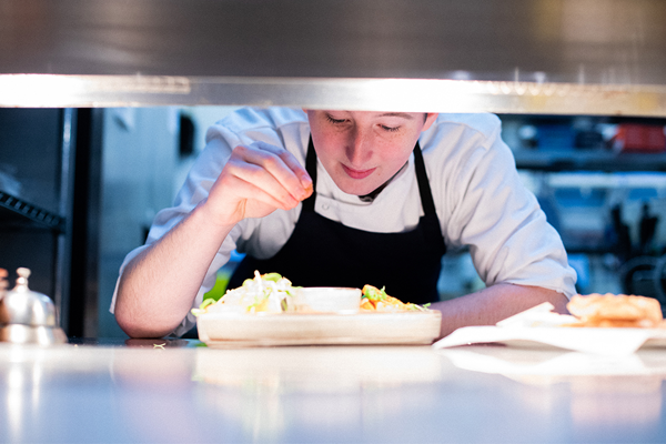 Catering student applying seasoning