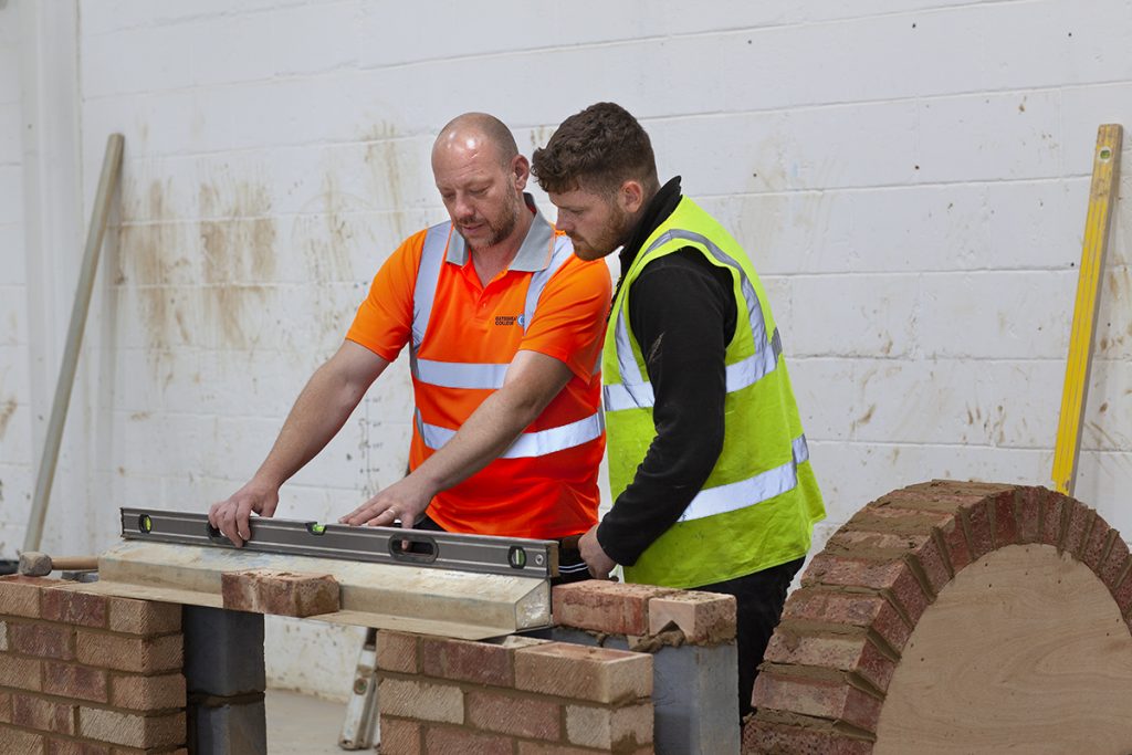 Construction teacher and student building a wall