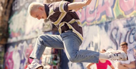 Dance student leaping in front of grafitti wall