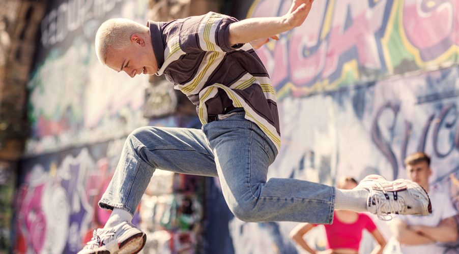 Dance student leaping in front of grafitti wall