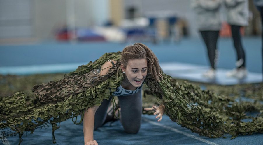 Female student army crawling under netting