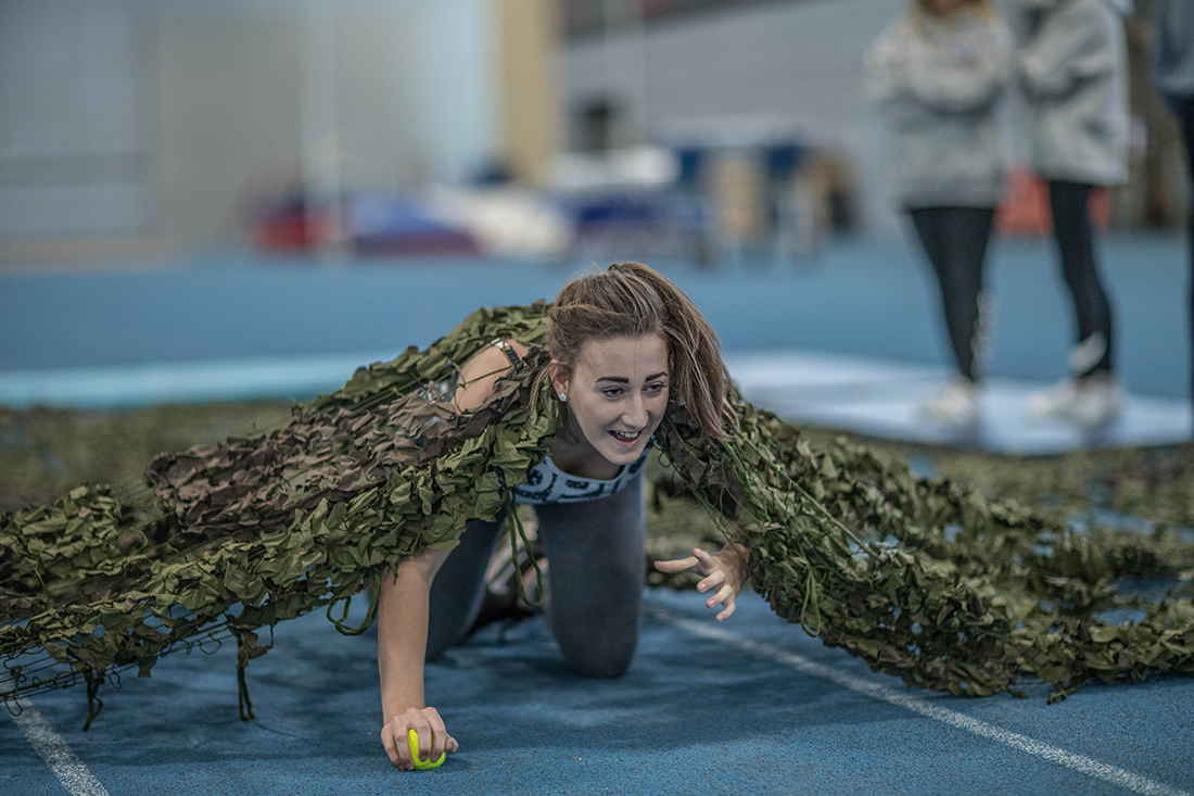 Female student army crawling under netting