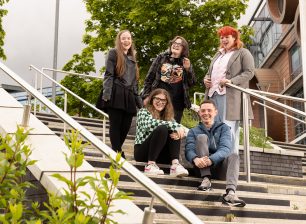 Group of students stood outside on stairs laughing with each other