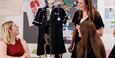 Healthcare students laughing with a fake skeleton