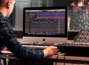 Music production studio desk with a singer in the soundbooth