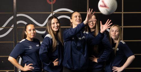 Netball team laughing whilst catching ball