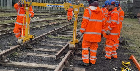 Rail workers moving equipment across the tracks