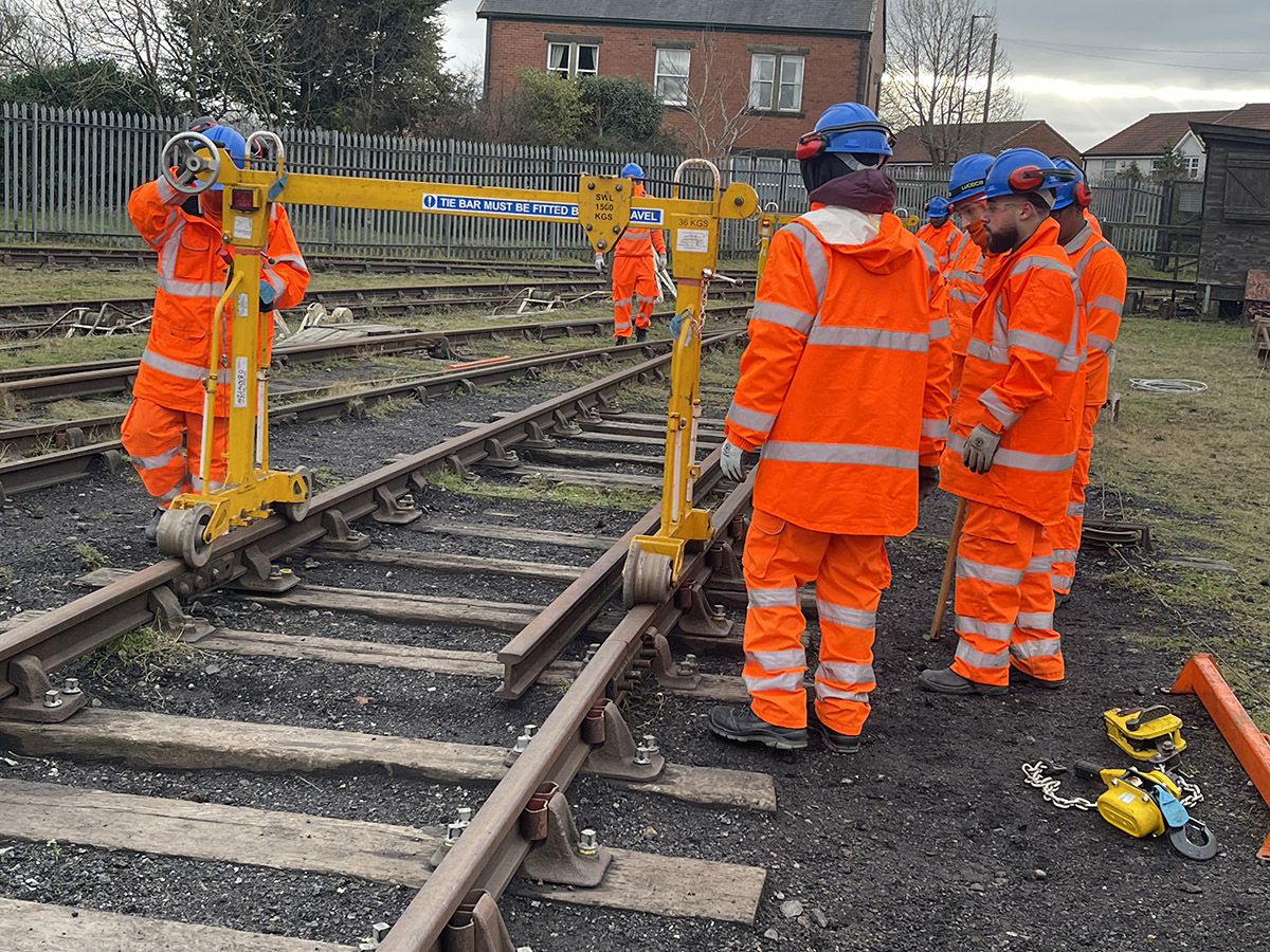 Rail workers moving equipment across the tracks