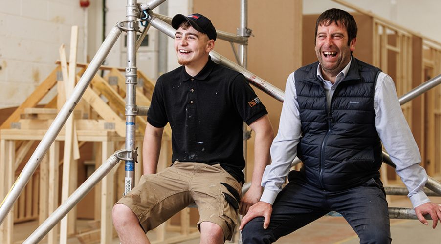 Student and teacher laughing whislt sat on scafolding