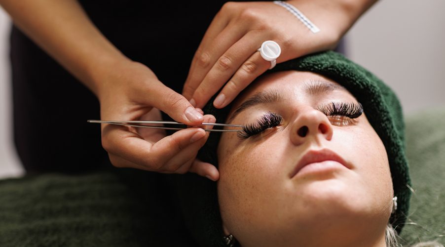 Student applying false lashes to a client