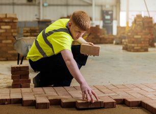 Student in high vis tshirt laying bricks