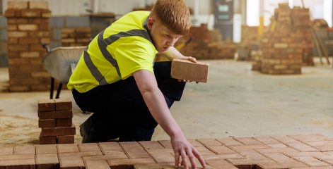 Student in high vis tshirt laying bricks