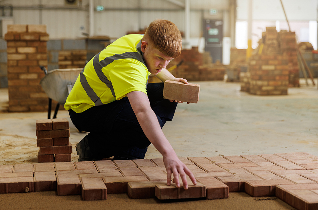 Student in high vis tshirt laying bricks