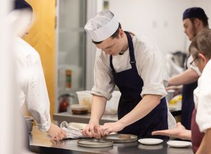 Student plating dish in kitchen
