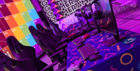 Gaming chairs and stations set up in front of large brightly coloured screen