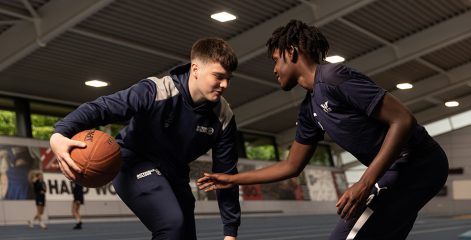 Two students playing basketball, wearing Gateshead College kit