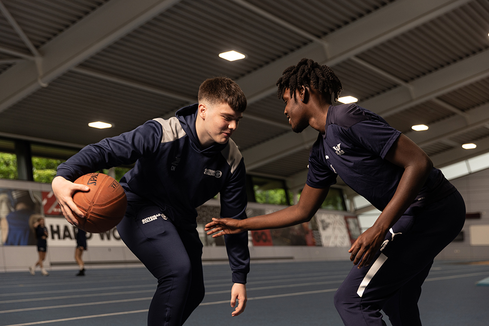 Two students playing basketball, wearing Gateshead College kit