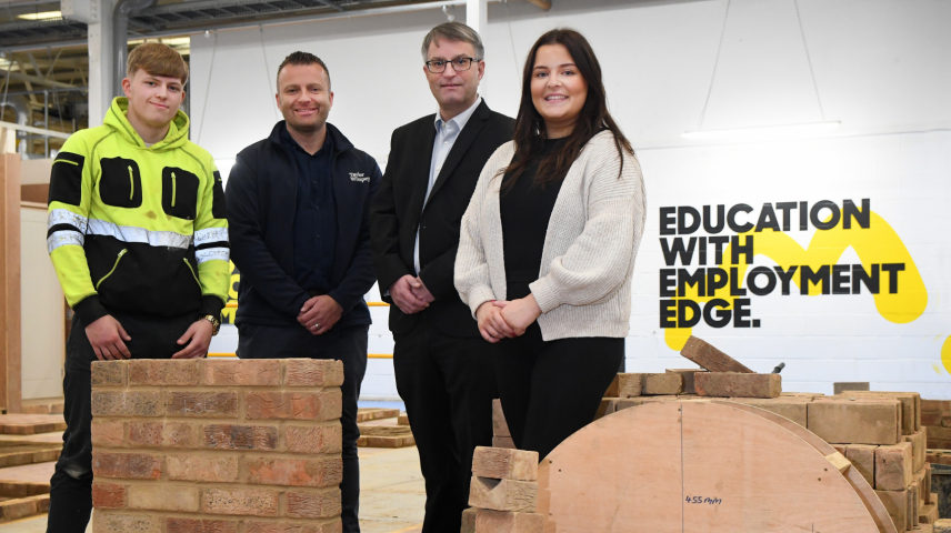 A group of four people stand in a construction workshop