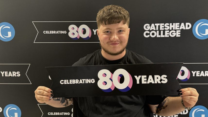 A young man holding a sign saying 'Celebrating 80 years'