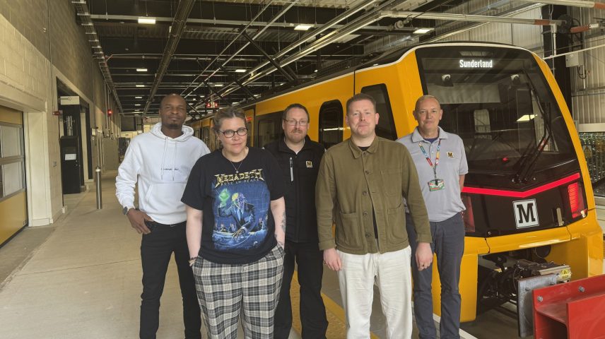 a group of people standing on a train platform with a train behind them.
