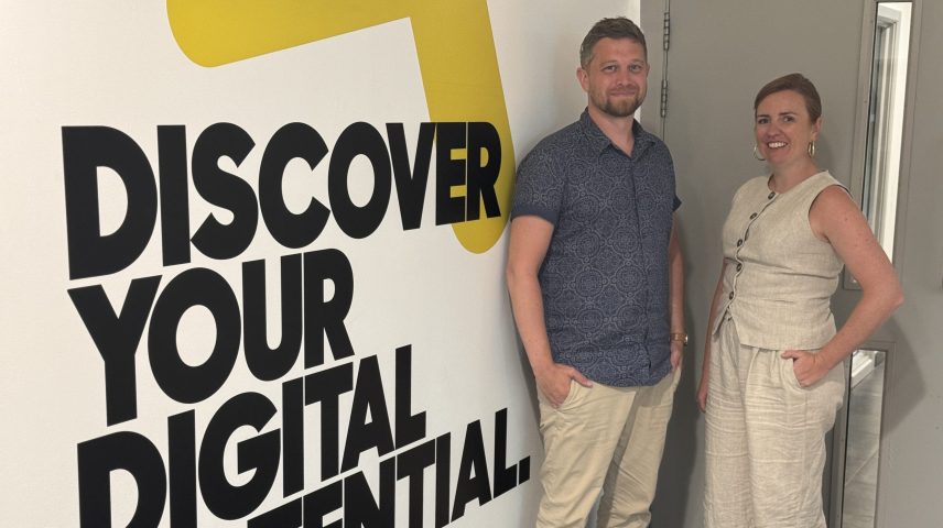 A man and a woman standing next to a wall that says 'Discover your digital potential'