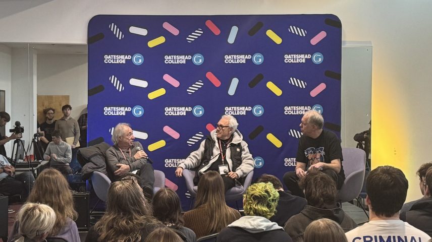 Three men sat on a stage talking to an audience.