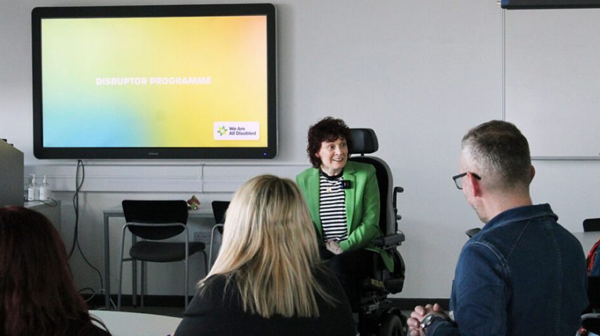 A lady in a wheelchair presenting to a room of people.
