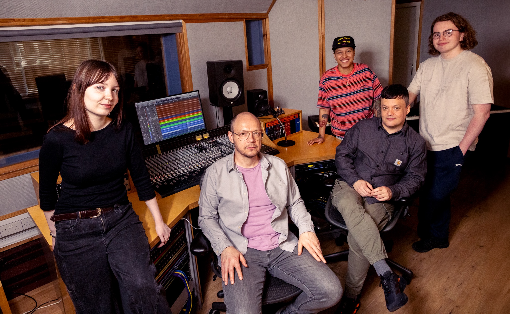 A group of men and women in a recording studio.
