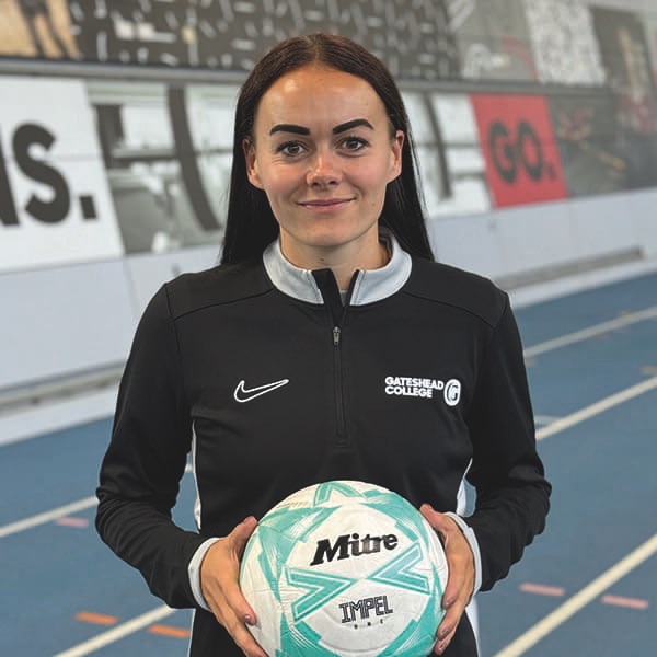 Woman wearing Gateshead College tracksuit top, holding a football.